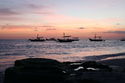 Silhouette boats moored on sea against sky during sunset