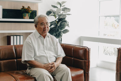 Senior man sitting on sofa at home