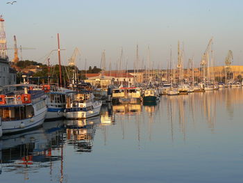 Boats moored at harbor against sky during sunset