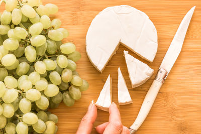 High angle view of hand holding a slice of cheese on table