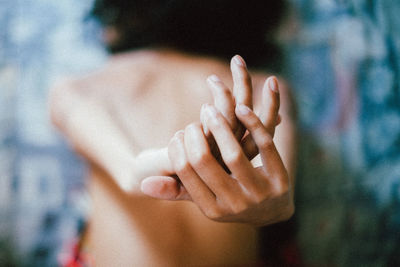 Rear view of young woman stretching hands on bed at home