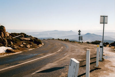 Road leading towards mountain against clear sky