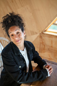 Happy latin woman smiling while sitting indoors.