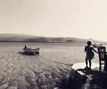 People standing on shore against clear sky