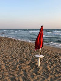 Red umbrella on beach against clear sky