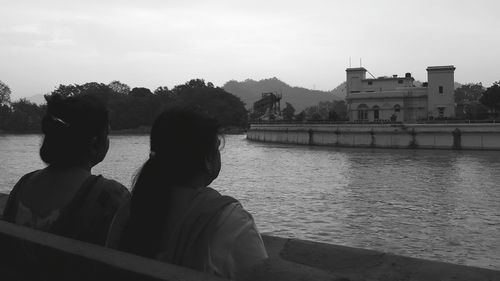 Rear view of people looking at river in city