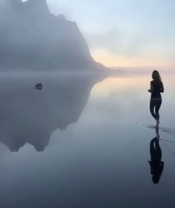 Silhouette man on sea against sky during foggy weather