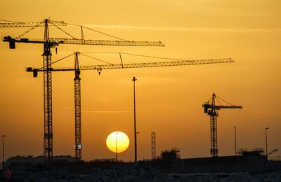 Cranes against sky at sunset