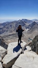 Full length of woman standing on cliff against mountain range