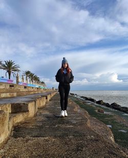 Full length of woman standing on sea against sky