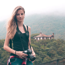 Portrait of beautiful woman standing against sky