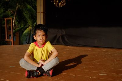 Full length portrait of cute boy sitting on floor