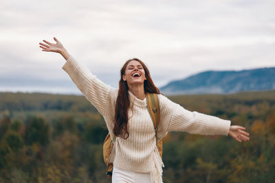 Portrait of young woman standing against sky