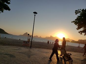 People on beach against sky during sunset