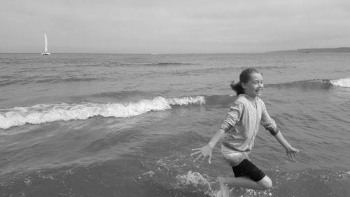Teenage girl running on shore against sky