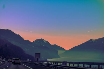 Road by mountains against clear sky during sunset