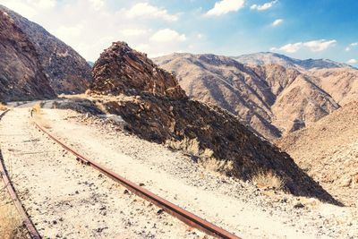 Railroad track by mountains against sky