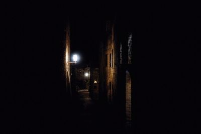 Illuminated street amidst buildings in city at night