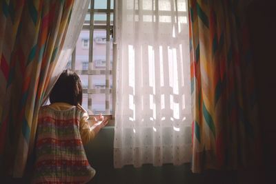 Girl looking through window at home