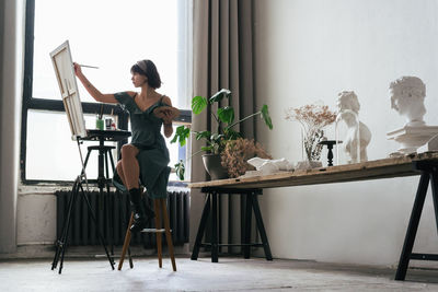 Low angle view of woman painting on canvas at art studio