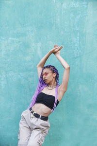 Woman with dyed hair standing against wall