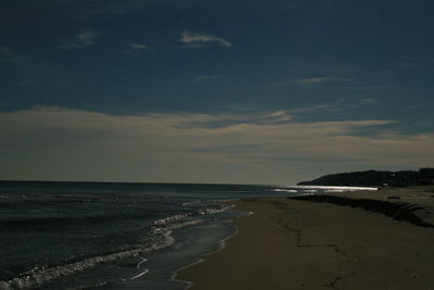 Scenic view of beach against sky at dusk