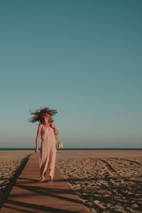 Woman standing on beach against clear sky