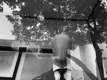 Woman by tree against sky in city