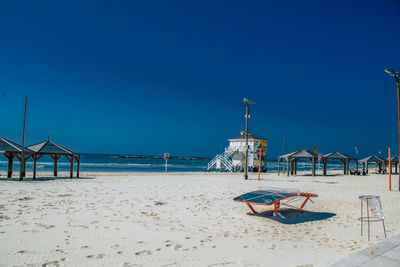 Lifeguard hut on beach against clear blue sky