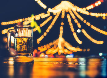 Close-up of illuminated candles on glass table