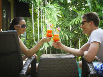 Couple toasting cocktail drinks at poolside