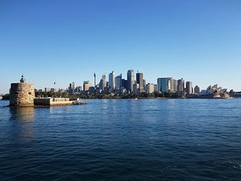 Sea by buildings against clear sky