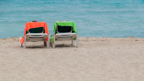 People relaxing on chairs at beach