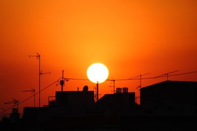 Low angle view of silhouette buildings against orange sky