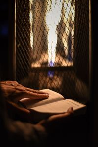 Cropped hands holding book by window