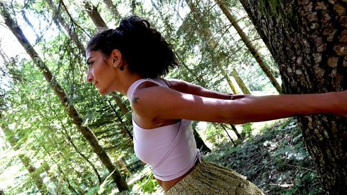 Side view of young woman exercising in forest