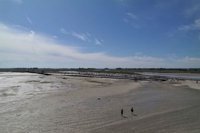 Scenic view of people on beach against sky