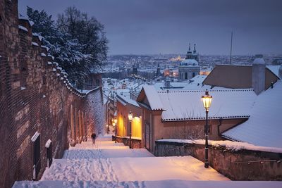 Cityscape of prague in winter. lonely man walking on staircase against lesser town early morning.