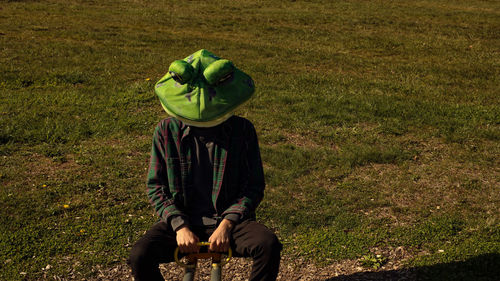 Rear view of person holding umbrella on field