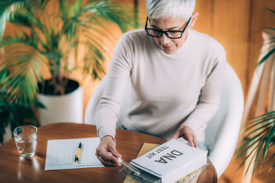 Midsection of woman using mobile phone while sitting on table