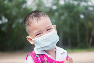 Portrait of boy wearing mask looking away standing outdoors