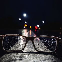 Close-up of sunglasses on illuminated street against sky at night