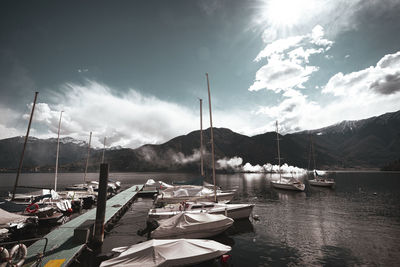 Boats moored at harbor against sky