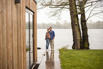 Pregnant woman standing with man on porch outside house