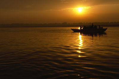 Silhouette boat in sea against sky during sunset