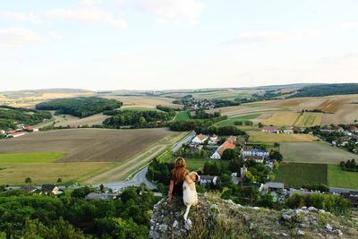 High angle view of woman with dog sitting on cliff against landscape