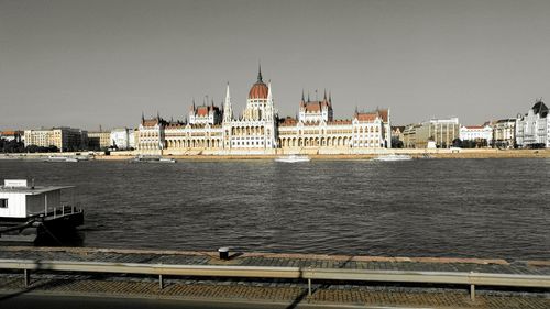 Hungarian parliament building by danube river against clear sky
