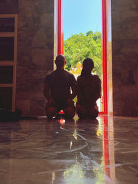Rear view of man and woman sitting on floor in building