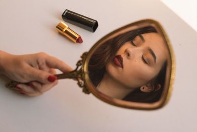 Cropped hand holding mirror with reflection