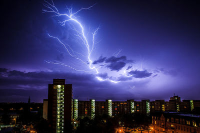 Lightning over illuminated buildings in city at night